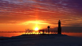 Winter sunrise time lapse of Algoma, Wisconsin lighthouse and steaming Lake Michigan waters with dramatic red sky, seamless loop.