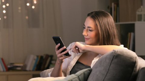 Happy woman using smart phone to share content on tv in the night at home