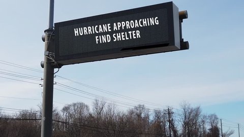 Electronic sign over highway warning that a hurricane is approaching and to find shelter