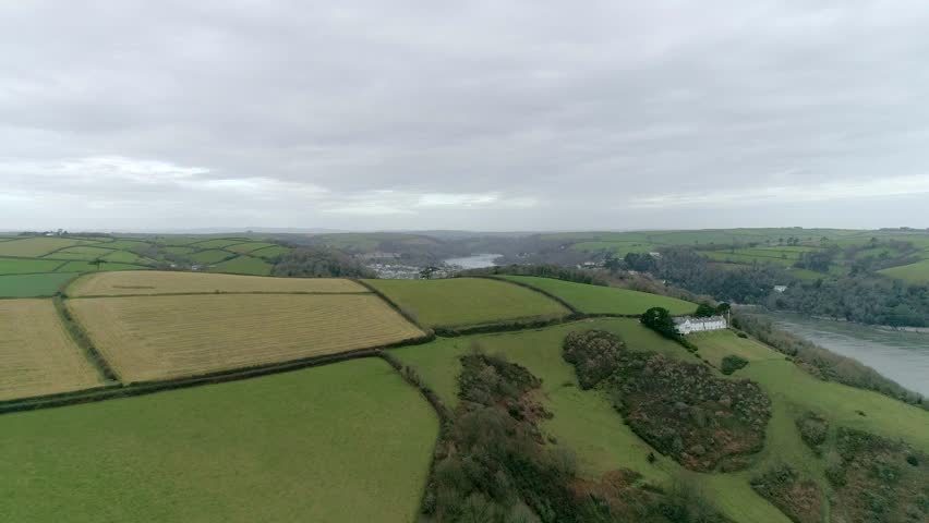 Aerial tracking over a satisfying arable field hill in the South Devon area. Behind the hill is the town of Dartmouth.
