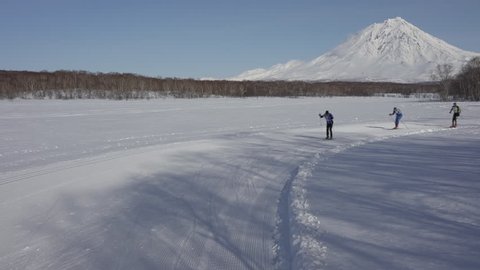 KAMCHATKA PENINSULA, RUSSIAN FAR EAST - FEB 9, 2019: Group of skiers running along winter ski track on sunny day on background of volcano. All-Russia mass ski race - Ski Track of Russian Federation.