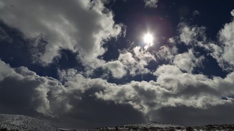 Time Lapse of Sun Clouds and Blue Sky with Snowy Desert Landscape.
