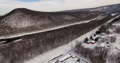 Aerial view moving forward over small rural town of Great Cacapon, West Virginia on the banks of the Potomac River with train tracks in the Appalachian mountains.