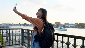 Young Asian female tourist backpacker taking selfie at viewpoint near Chao Phraya river in Bangkok Thailand