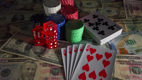 Gambling items with light source moving from right to left and back again casting shadows over US $ Dollar Banknotes, Playing Cards, Poker Chips and Dice