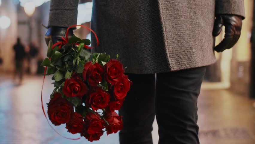 Low section of man holding a bunch of red roses 