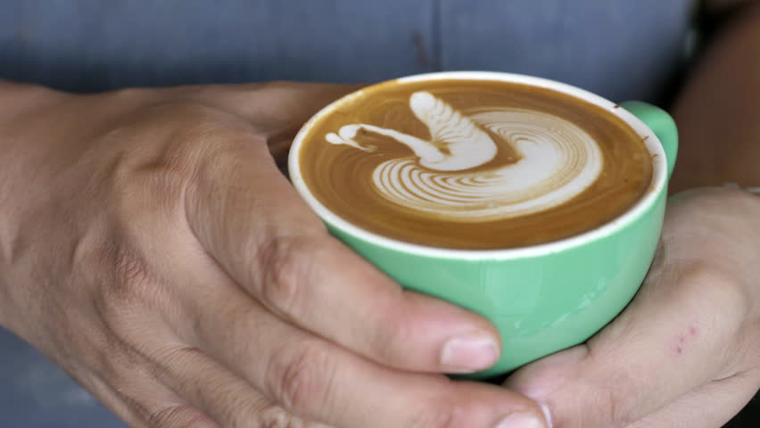 Professional Barista with coffee cup making beautiful latte art pattern.