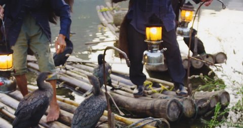 Cormorant fisherman placing their lanterns on bamboo rafts at sunset on Li River, Xingping,  Guilin, Guangxi Province, China. Slow-motion, hand held, Red cinema camera. 
