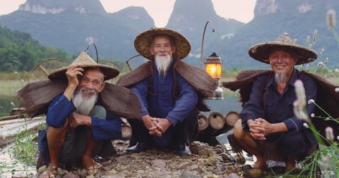 Portrait of a group, cormorant fisherman on bamboo rafts at sunset on Li River, Xingping,  Guilin, Guangxi Province, China. Slow-motion, hand held, Red cinema camera. 