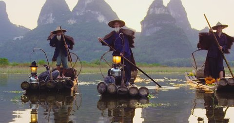 Cormorant fisherman paddling on Li River with there bamboo rafts at sunset, Xingping,  Guilin, Guangxi Province, China. Slow-motion, hand held, Red cinema camera. 