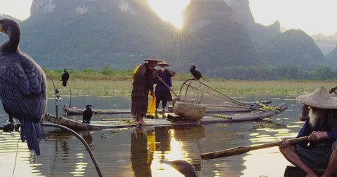 Cormorant fisherman throwing a fishing net in the Li River on his bamboo raft at sunset, Xingping,  Guilin, Guangxi Province, China. Slow-motion, hand held, Red cinema camera. 