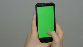 Teen boy holds in hand a black smartphone with a green screen on a white background. Technology