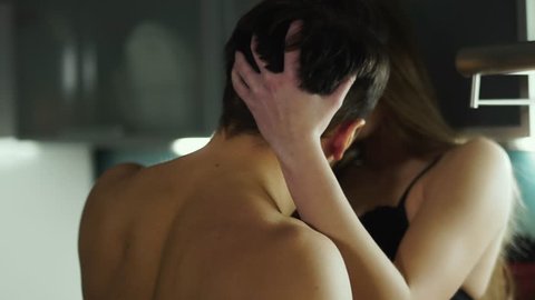 Young hot couple kissing passionately in the kitchen, the girl is touching guys hair, and the guy is kissing her in neck