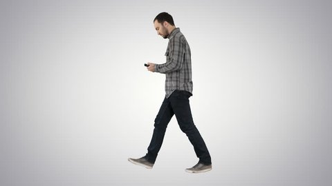 Young bearded man walking and talking on the mobile phone on gradient background.