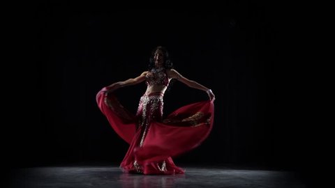 Belly dancer girl continue dance in chiffon dress . Black background