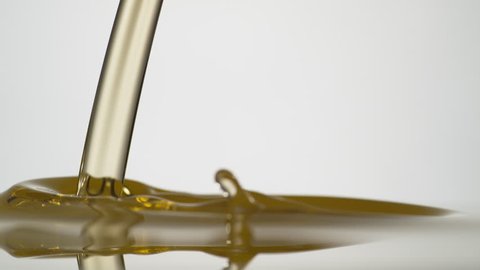 Golden oil pouring against white background. Shot with high speed camera, phantom flex 4K. Slow Motion. Unedited version is included at the end of clip.