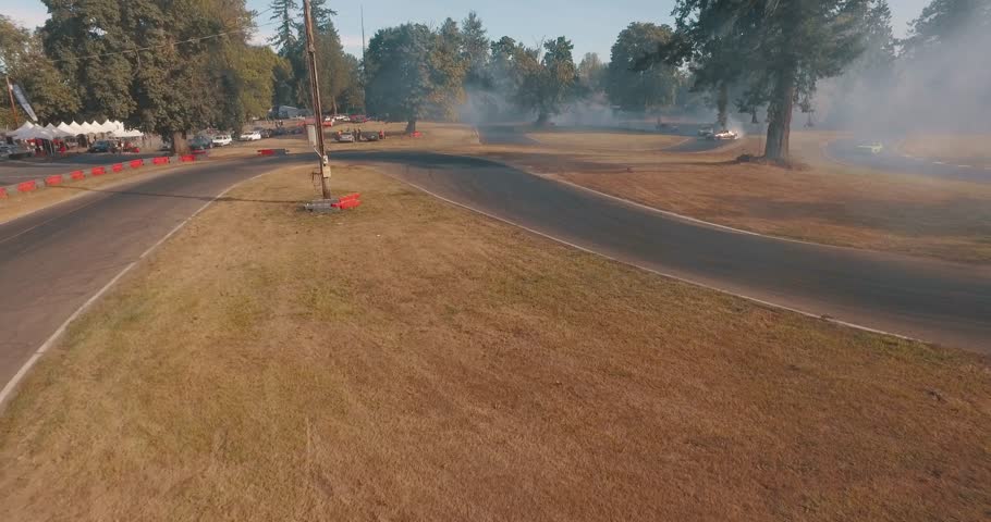Fast Paced Low Aerial Drone Tracking Shot of Multiple Cars Drifting Around a Corner.