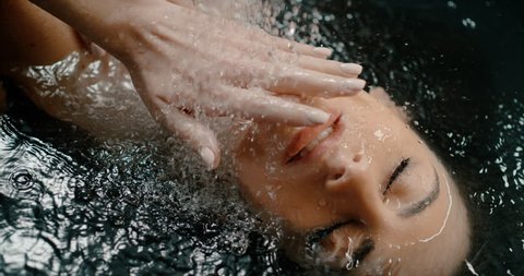 slow motion of a beautiful young woman washing herself in a bathtub, black water. sensual girl enjoying life saressing herself