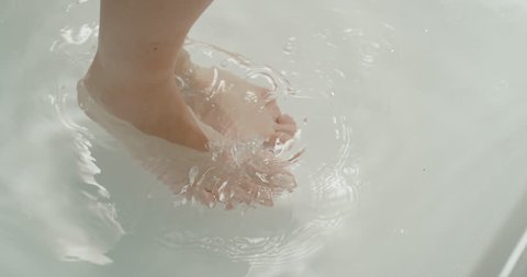slow motion of a woman feet entering in the water for a bath. sensual feet of a beautiful girl