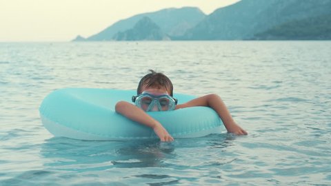 Little boy sleeping on rubber ring swimming in sea. Child relaxing on inflatable circle during summer holidays. Kid floating on inflatable circle in sea