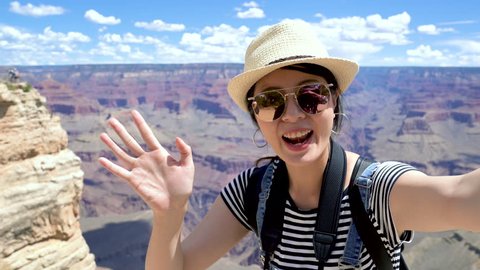 happy college girl student exchange studying in america sightseeing on summer vacation in Grand Canyon National Park arizona usa. young asian woman waving hand talking video phone call sending kiss