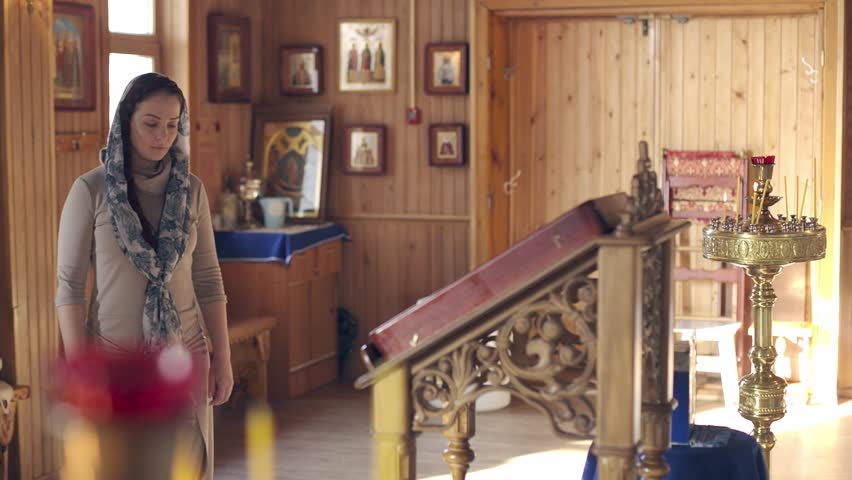 lifestyle woman praying in Church in front of icons, Russian Orthodox wooden Church, view inside
