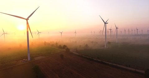 Aerial view of Wind turbines Energy sunrise in forest with fog. Production by of drone footage 4k aerial shot on sunrise. with environment friendly renewable energy concept.
