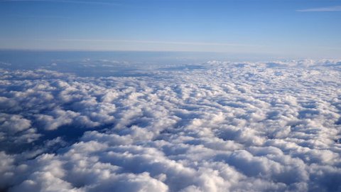 Stunning footage of aerial view above clouds from airplane window with blue sky. view from the airplane window to the blue sky and white clouds. ravelling by air background. Real time footage