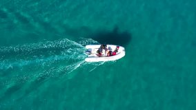 Aerial top view video of small inflatable cruising in low speed in exotic bay with emerald sea