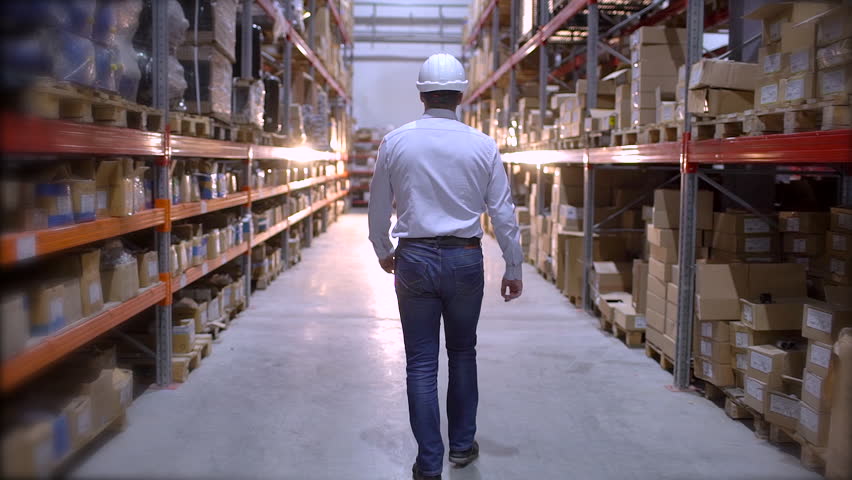 Follow footage of employees male warehouse worker engineer in hard hat working. walking through logistics center warehouse factory construction site logistics architect businessman man builder indoors Royalty-Free Stock Footage #1023949862