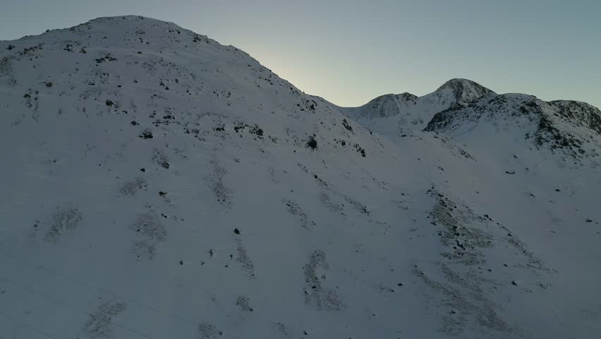 Aerial view of Hellisheidi powerplant in winter and mountain above it, snow covered ground and still weather with steam rising up