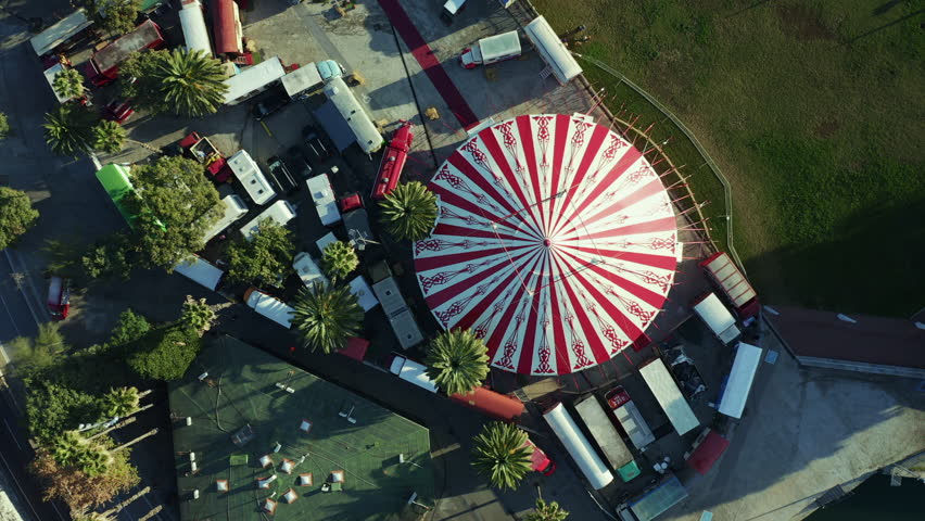 Aerial; drone view of bright round dome of street circus chapiteau; warm morning light on the roof of travelling circus; attractions for tourists and locals; used for theater and entertainment events Royalty-Free Stock Footage #1023965513
