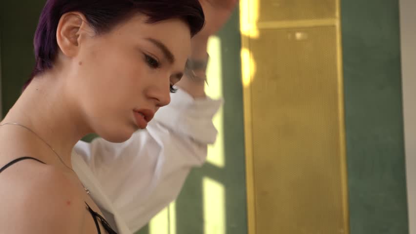 A woman with purple hair and blue eyes, dressed in black underwear, stockings and a white man