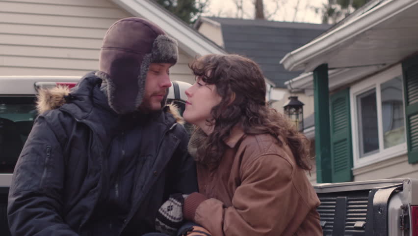 Young romantic couple on back of pickup truck kiss in slow motion