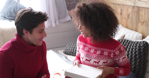 Woman opening christmas gift and embracing her boyfriend