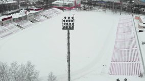 winter outdoor stadium, a tower with spotlights, stadium arena lighting, aerial video photography from a quadrocopter