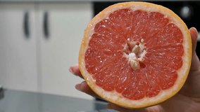 Close up video of female hand holding a ripe half of grapefruit.
