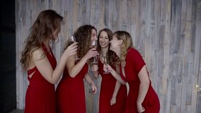Hen Party: Four girls in red dresses having fun, drinking champagne and talking.