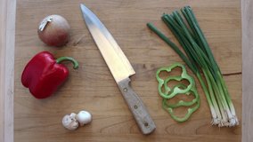 A video clip of cutting mushrooms and other vegetables waiting to be cut on a cutting board.