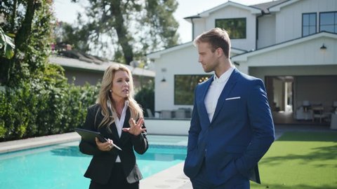 Realtor woman showing a new home to a wealthy client at open house 