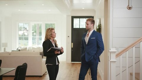 Realtor woman 50s showing a property to young businessman at open house / Selling Real estate 