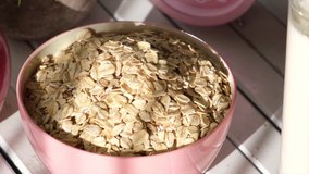 Oatmeal cereal in pink bowl on wooden table top. Selective focus. Panning to the right.