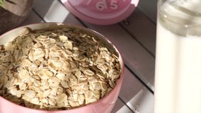 Oatmeal cereal in pink bowl on wooden table top. Selective focus. Panning to the left.
