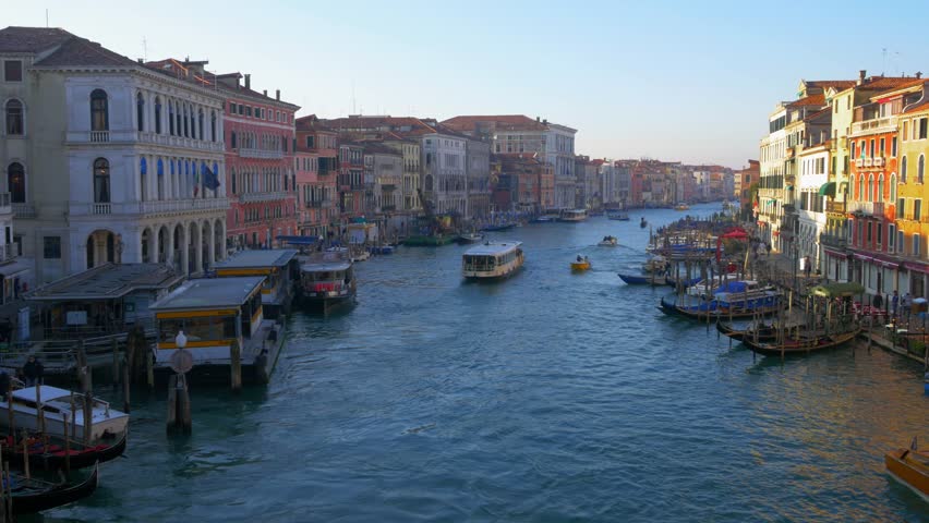 Beautiful Venice canal with boat traffic with gondolas and boats anchored to the shores at sunset. Venice Italy. Flat plane