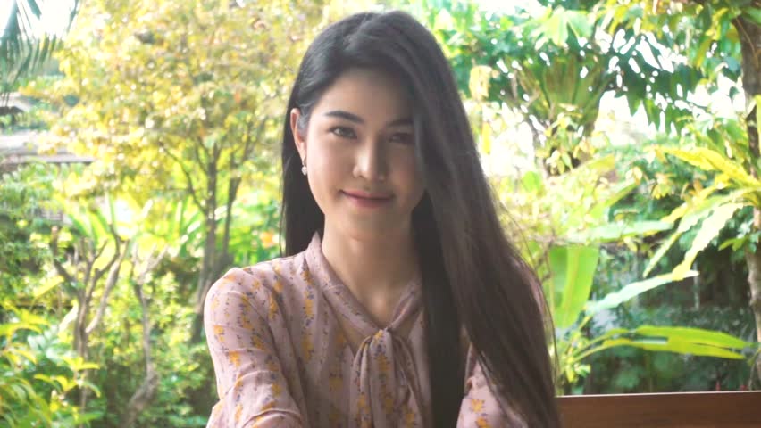 Asian women with long hair smiling bright look good sitting in the garden at her home.
