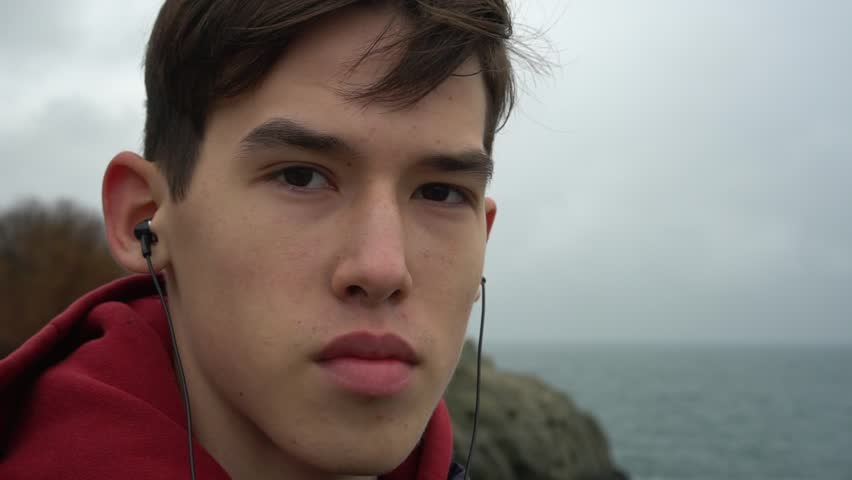 Portrait Of Handsome Young Mixed Race Man Unhappy Worried Looking At Camera Sad. Sea coast windy cloudy day