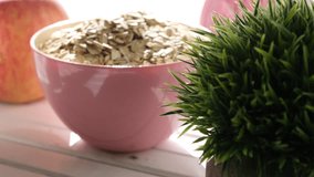Oatmeal cereal in pink bowl on wooden table top. Selective focus. Tracking shot.