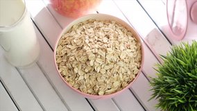 Oatmeal cereal in pink bowl on wooden table top. Selective focus. Top view tracking shot.