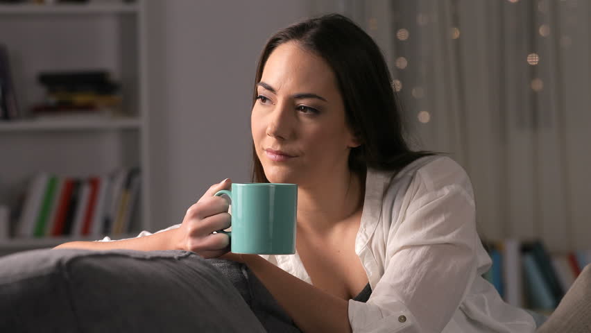 Serious pensive woman drinking coffee sitting on a couch at home in the night Royalty-Free Stock Footage #1024023752