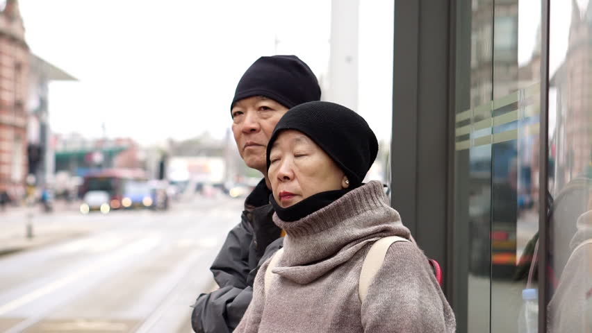 Asian Elderly Couple Waiting For Bus In Backpacking Trip Travel Europe